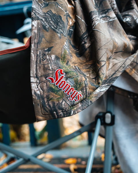 Camouflage blanket with 'Stoney's' logo on a blurred outdoor background
