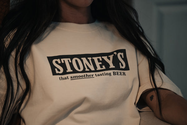 Person wearing a beige t-shirt with 'STONEY'S' text design.